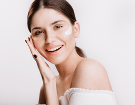 girl-touches-moisturized-skin-smiles-portrait-model-with-cream-face-isolated-wall